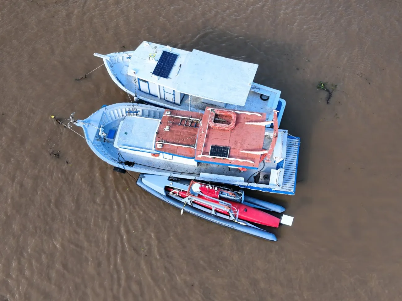Vista aérea do USV Exail DriX a contrabordo das embarcações de apoio.