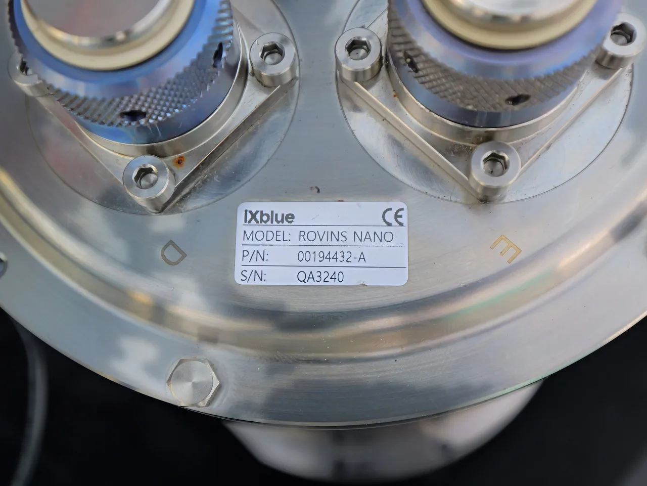 Placa de identificação da central inercial iXblue Rovins Nano entre os conectores.