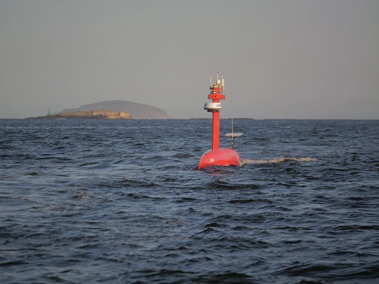 USV Exail DriX em navegação visto de frente, com o mastro de antenas e a antena GNSS de popa.