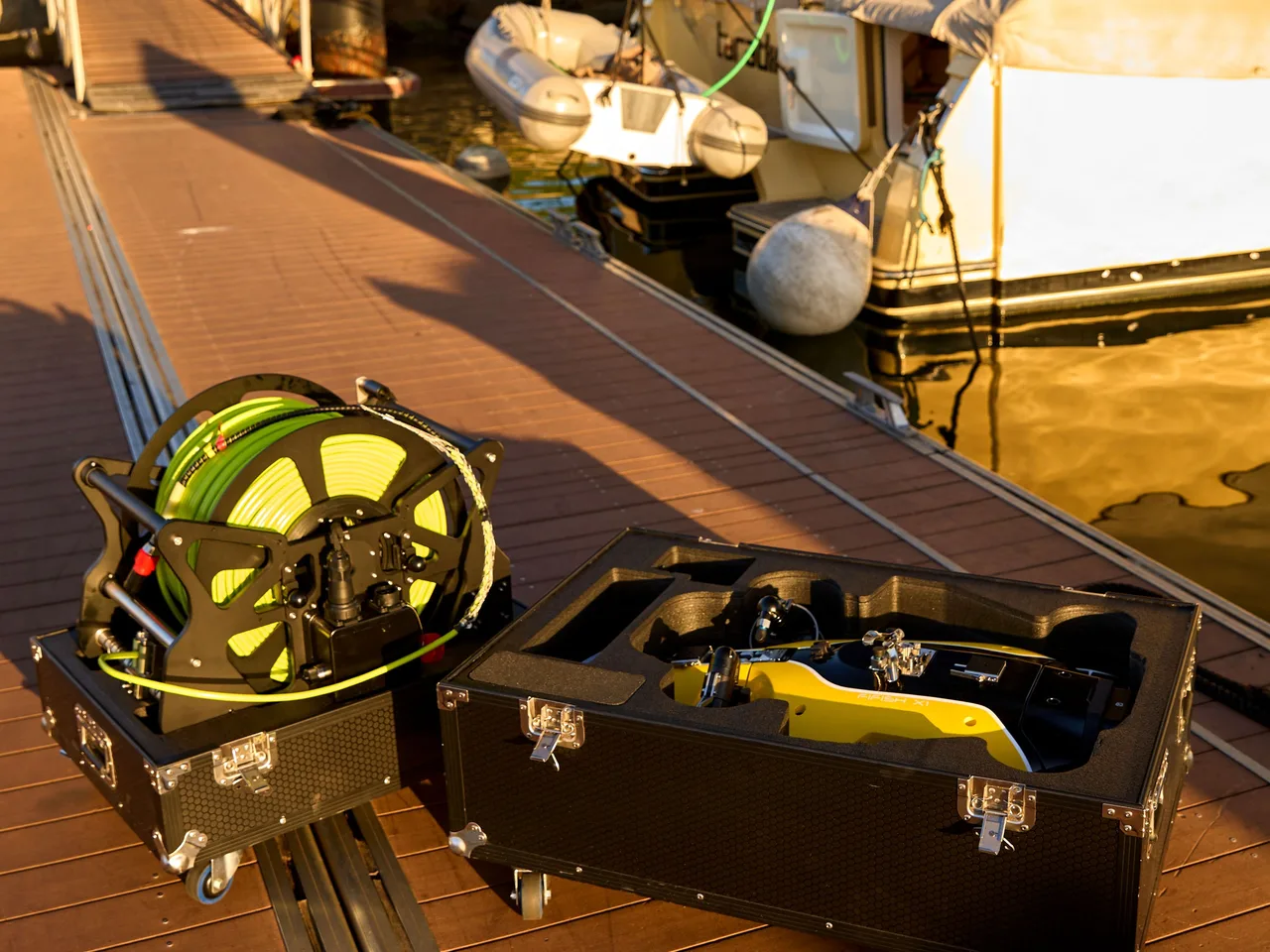 Kit ROV QYSEA FIFISH X1 no pier: carretel do cabo umbilical e case de transporte aberto com o ROV.