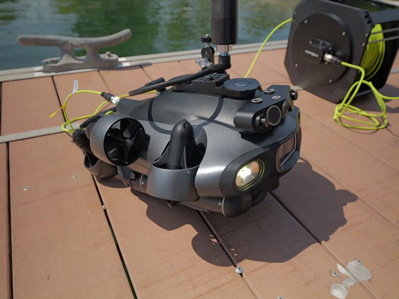 ROV QYSEA FIFISH E-Master sobre pier, com o cabo umbilical amarelo e o carretel ao fundo.